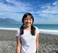 headshot of angela standing on a beach with ocean in background